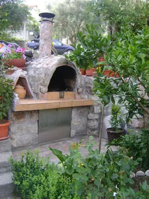 a stone oven in a garden with potted plants at Apartments Kovačević in Petrovac na Moru