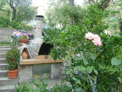 a stone oven with potted plants in a garden at Apartments Kovačević in Petrovac na Moru