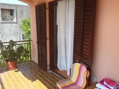 a chair sitting on the balcony of a house at Apartments Kovačević in Petrovac na Moru
