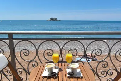 a table with two glasses of orange juice on a balcony at Beach House in Petrovac na Moru