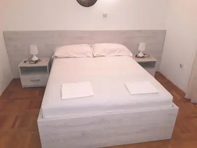 a bedroom with a white bed with two night stands at Apartments Đurašević Ivo in Sveti Stefan