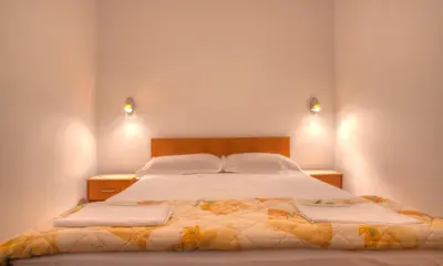 a bedroom with a large bed with two lights on the wall at Apartments Đurašević Ivo in Sveti Stefan