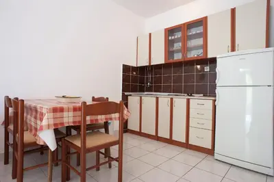 a kitchen with a table and a white refrigerator at Apartments Đurašević Ivo in Sveti Stefan