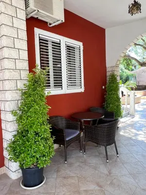 a patio with a table and chairs and a red wall at Apartments Boreta II in Budva