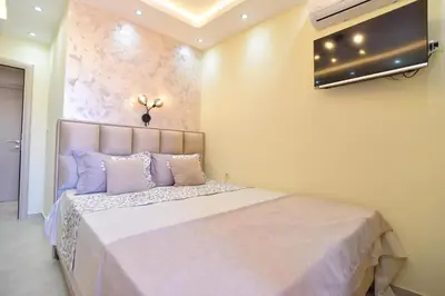 a bedroom with a bed with a television on the wall at Vila Apartments Lidija in Petrovac na Moru