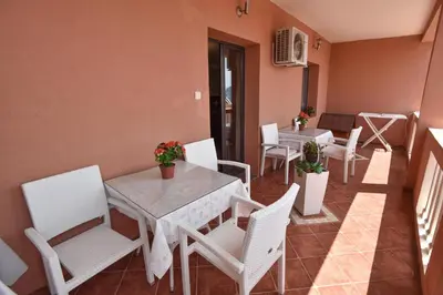 a dining room with white chairs and a table and tables at Vila Apartments Lidija in Petrovac na Moru