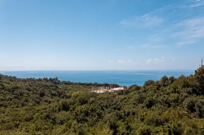 a house on a hill with the ocean in the background at Vera Apartments in Ulcinj