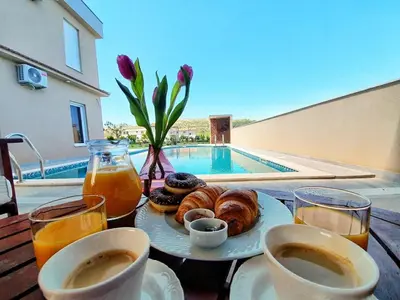 a breakfast of coffee and donuts on a table next to a pool at Vila Uma in Bar