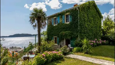 a house covered in ivy next to the water at Holiday Homes Sunset Hill in Sveti Stefan