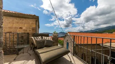 a balcony with a chair and a table on a roof at Holiday Homes Sunset Hill in Sveti Stefan
