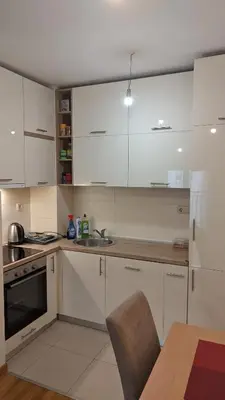 a kitchen with white cabinets and a sink and a table at Guest House Mikeli (BESPL. DORUCAK)-(FREE BREAKFAST) in Podgorica
