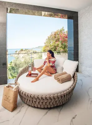 a woman sitting on a round bed in a room with a window at Villa Geba Boutique Hotel in Sveti Stefan