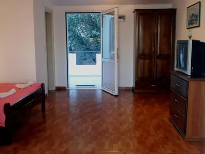 a living room with a television and a sliding glass door at Oaza Guest House in Sveti Stefan