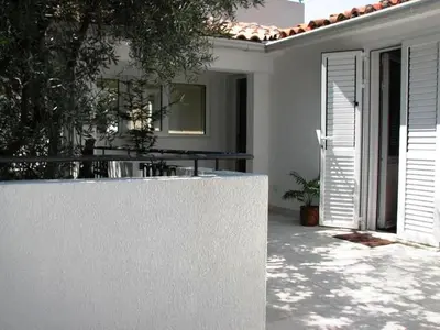 a white house with a porch with a table at Oaza Guest House in Sveti Stefan