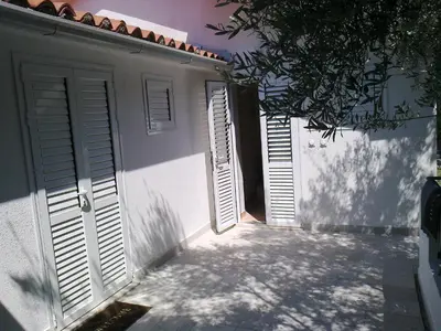 a pair of shuttered doors on a white building at Oaza Guest House in Sveti Stefan