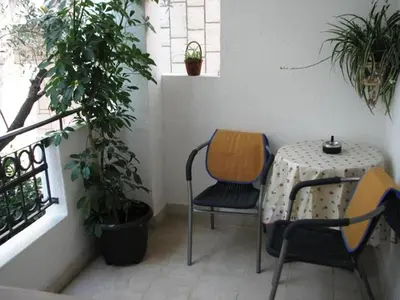 a table and chairs on a balcony with plants at Oaza Guest House in Sveti Stefan