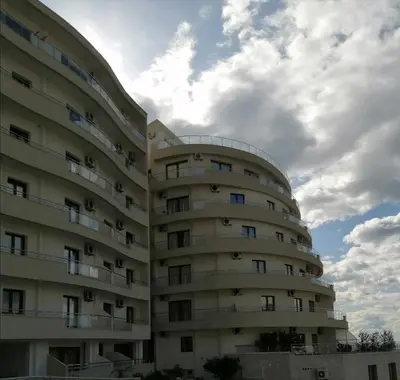 a large apartment building with a cloudy sky in the background at Apartman Sadutas in Rafailovici