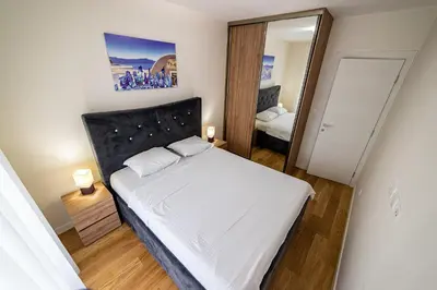 a small bedroom with a bed and a mirror at Apartments Centrale 28 in Podgorica