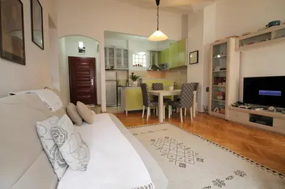 a living room with a white couch and a kitchen at Meric Duplex Apartment in Budva