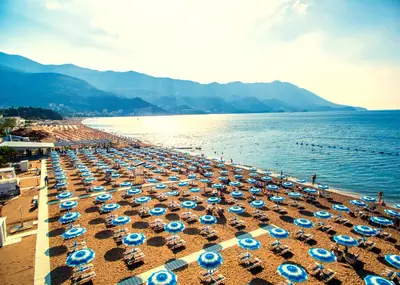 a beach with many blue and white umbrellas at Meric Duplex Apartment in Budva