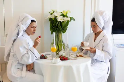 two women in white robes sitting at a table with breakfast at Boutique Hotel Vissi d'Arte in Budva
