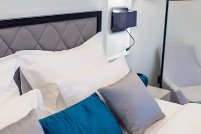 a bed with white and blue pillows on it at Boutique Hotel Momentum by Aycon in Budva