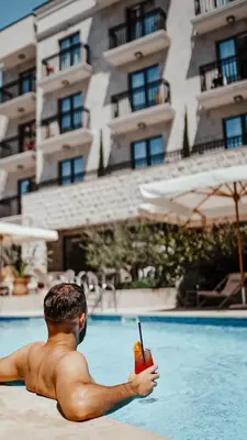 a man sitting in a swimming pool with a drink at Boutique Hotel Momentum by Aycon in Budva