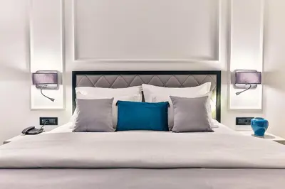 a white bedroom with a large bed with blue pillows at Boutique Hotel Momentum by Aycon in Budva