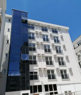 a tall white building with blue windows at Anja apartment_City Center_ in Bar