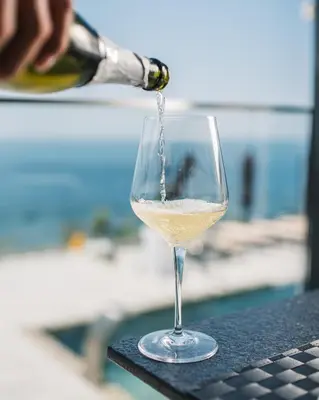 a glass of white wine is being poured at Dollaku Apartments in Bar