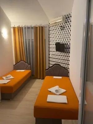 two beds in a room with yellow curtains at SARA BUDVA in Budva