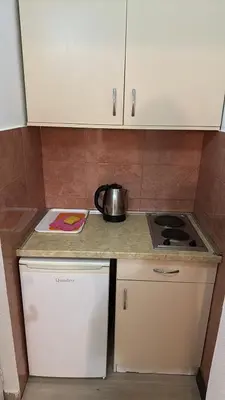 a small kitchen with a stove and white cabinets at SARA BUDVA in Budva