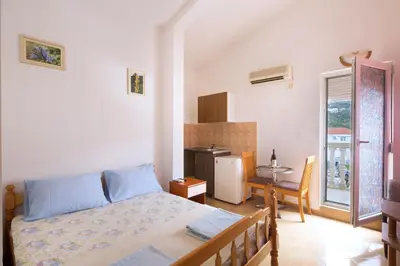 a bedroom with a bed and a table and a kitchen at Apartments Antic in Budva
