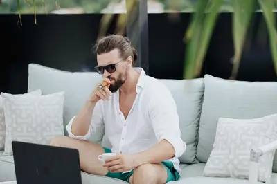 a man sitting on a couch with a laptop at AM Palace in Ulcinj