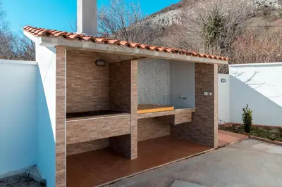 a brick barbecue with a roof on a house at Holiday Home Marija in Budva