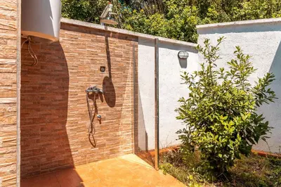 a shower in a brick wall next to a bush at Holiday Home Marija in Budva
