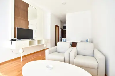 a living room with two white chairs and a tv at BARBETA Accommodation in Budva