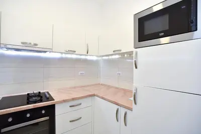 a white kitchen with a microwave and a refrigerator at BARBETA Accommodation in Budva