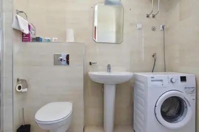 a bathroom with a toilet sink and a washing machine at BARBETA Accommodation in Budva