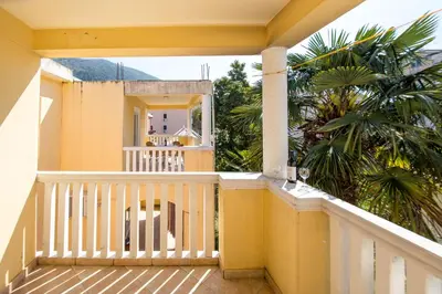 a balcony of a yellow house with a palm tree at Apartments Angela in Budva