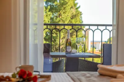 a table with a bottle of wine and glasses on a balcony at Luxury Apartments Queen in Petrovac na Moru