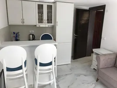 a kitchen with white cabinets and white stools at Apartment Apollo 2 in Kotor