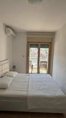 a large white bed in a room with a window at Fontana Mediteran Properties in Budva