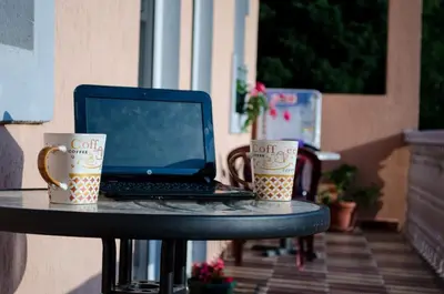 a laptop sitting on a table with two coffee cups at Apartments Lazarević Sutomore in Sutomore