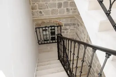 a staircase in a stone building with a black railing at Palazzo Sindik in Kotor