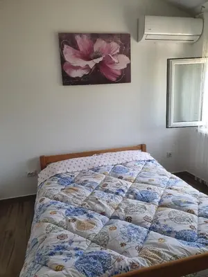 a bed in a bedroom with a flower picture on the wall at NEÐO Apartments Brda in Tivat