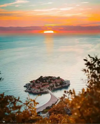 an island in the middle of the water with the sunset at Apartments Petar in Budva
