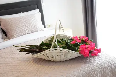 a basket with pink flowers on a bed at Apartments Petar in Budva