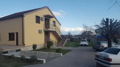 a house with cars parked in a parking lot at Hostel Vera - Airport Podgorica in Podgorica