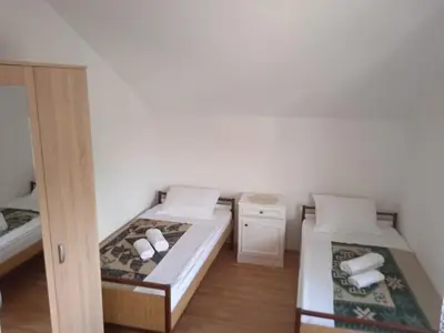 a small room with two beds and a door at Hostel Vera - Airport Podgorica in Podgorica